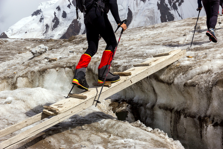 market adjacency strategy: hiker walking across a wooden bridge across ice on a mountain