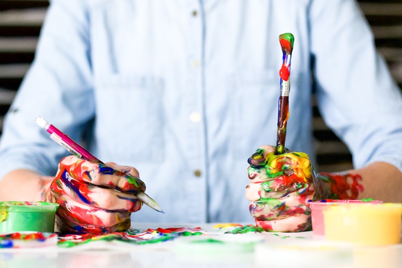 business problems: man holding a paint brush and pencil covered in paint